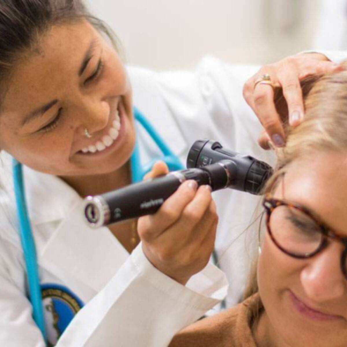 A Physician Assistant looking in the ear of her patient